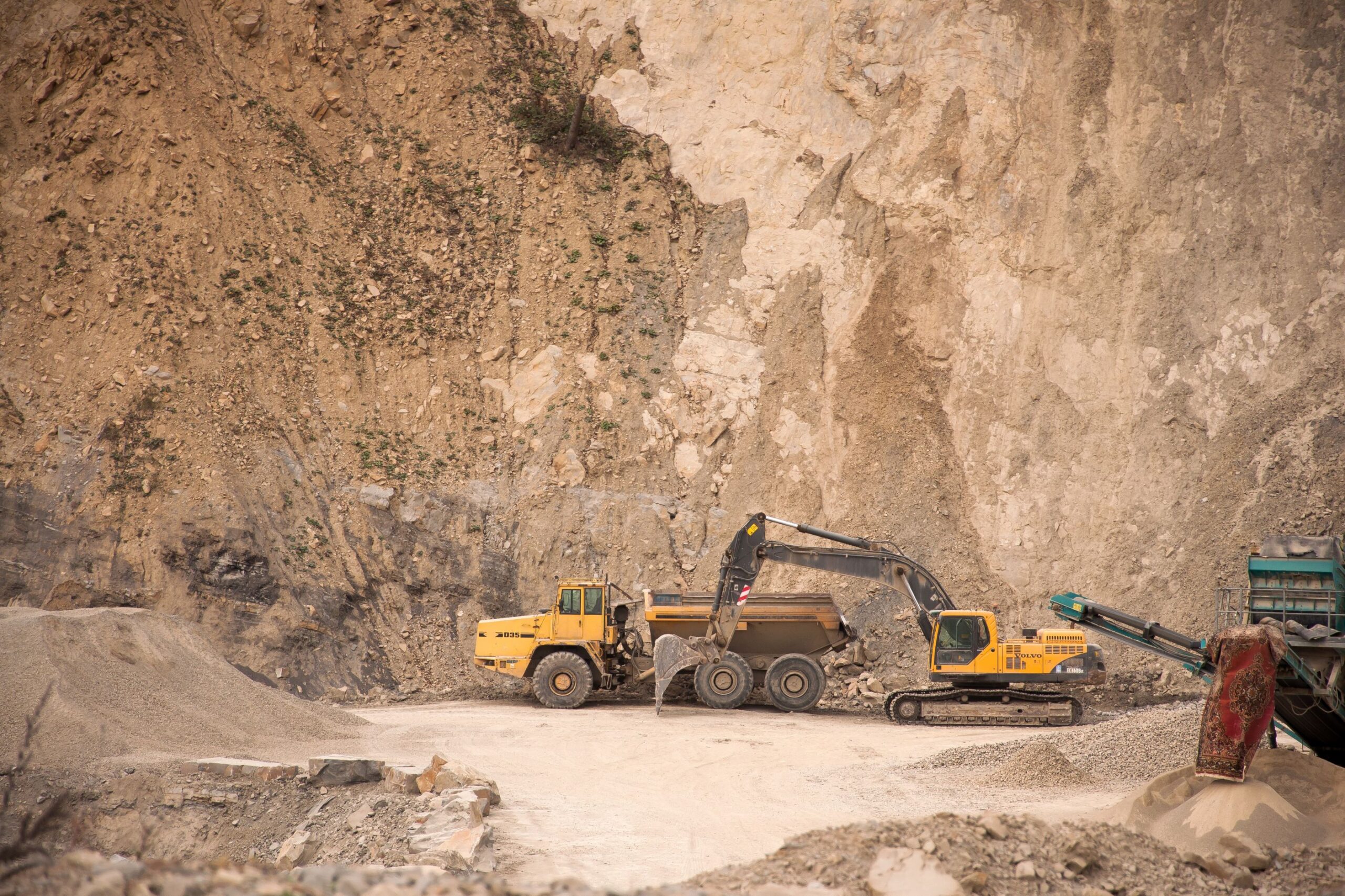 Excavator loading a haul truck against a quarry face at an open cut operation